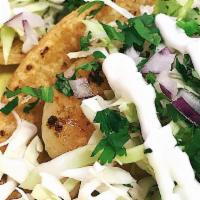 Fish Taco · Battered fish, cabbage, cilantro and onions topped with baja cream sauce.