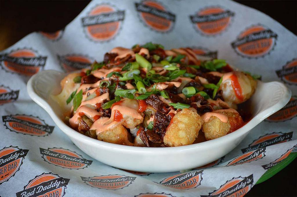 Atomic Tots · Crispy tots topped with our Amber Ale queso, Pepper jack cheese, jalapenos, Sriracha sour cream, jalapeno bacon crumbles, green onion and even more Sriracha.