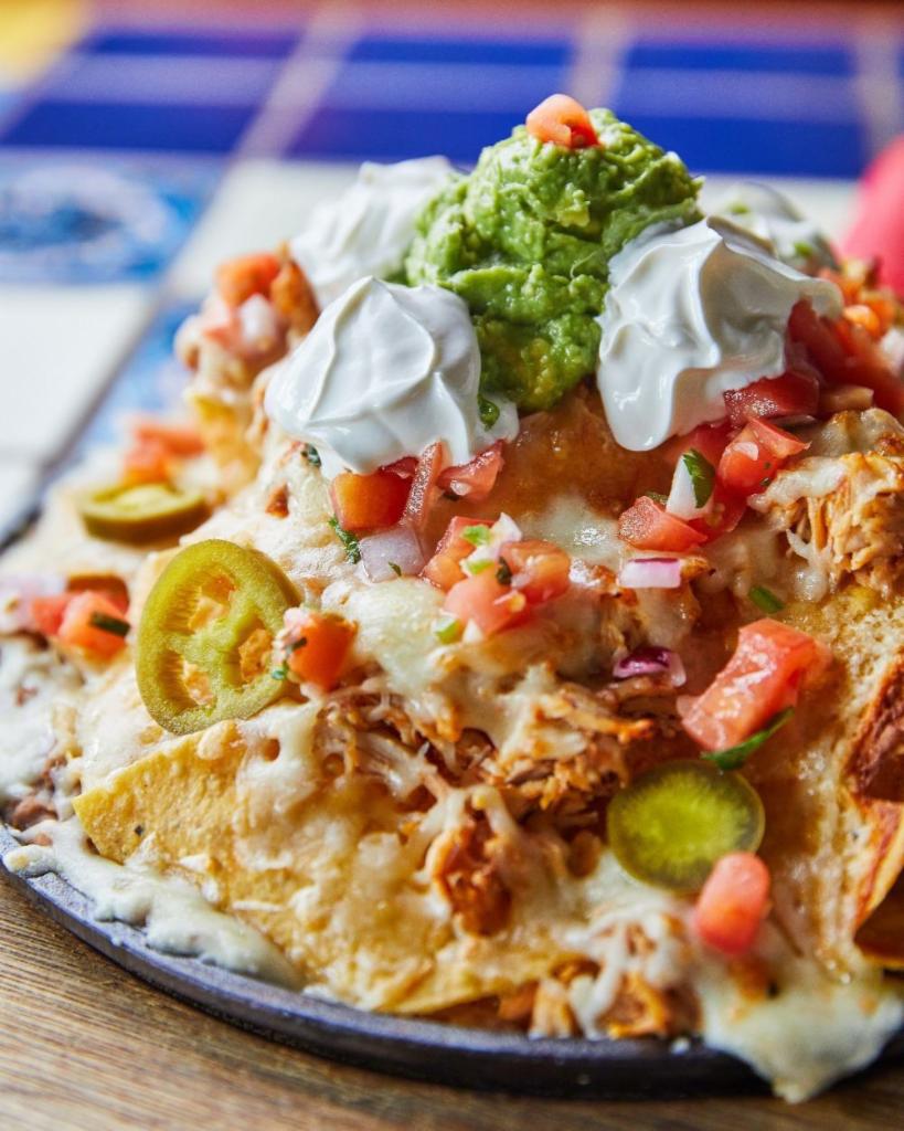 Loaded Skillet Nachos · You ready for this? House-fried chips over a bed of refried beans, double layered with chicken or beef, smothered with queso, jack and cheddar cheeses, served with jalapenos, guacamole, salsa fresca and and sour cream. Can be made vegetarian.
