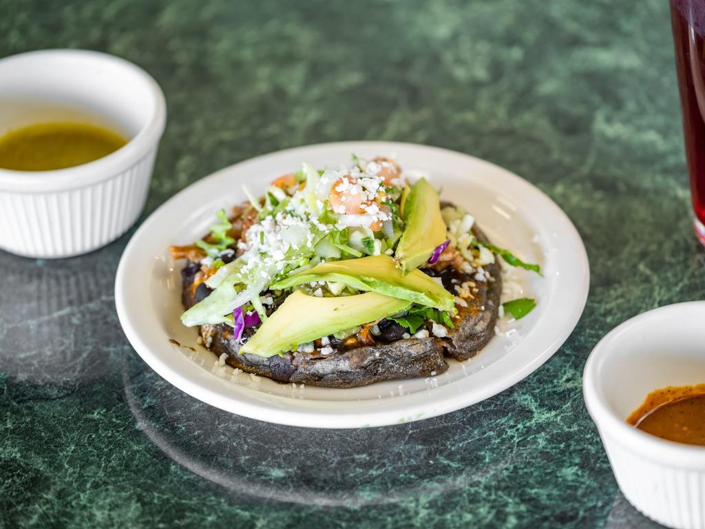 Picaditas · Handmade organic thick tortilla topped with black beans, avocado, cabbage, queso fresco, sour cream, and choice of filling. Vegan. Gluten free.