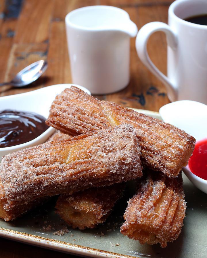 Churros · Hot Mexican doughnuts dusted with sugar 
and cinnamon. Served with dark chocolate  
and raspberry-guajillo dipping sauces.