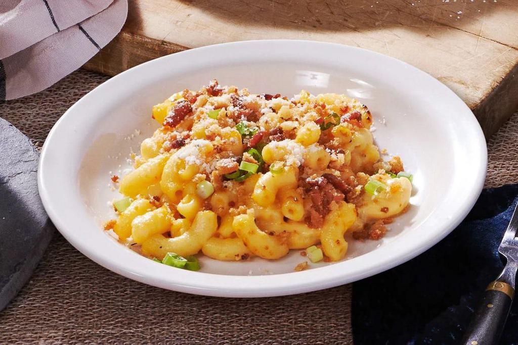 Bacon Mac n’ Cheese · There's a new way to enjoy a classic. Our creamy mac n' cheese comes topped with crispy bacon bites, parsley, green onions, and parmesan cheese. 

