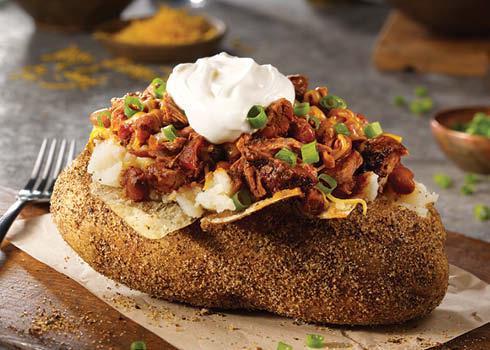 Brisket Chili Baker. · A giant smoked baker with margarine, sour cream, shredded cheddar cheese, green onions, and topped with our Brisket Chili.