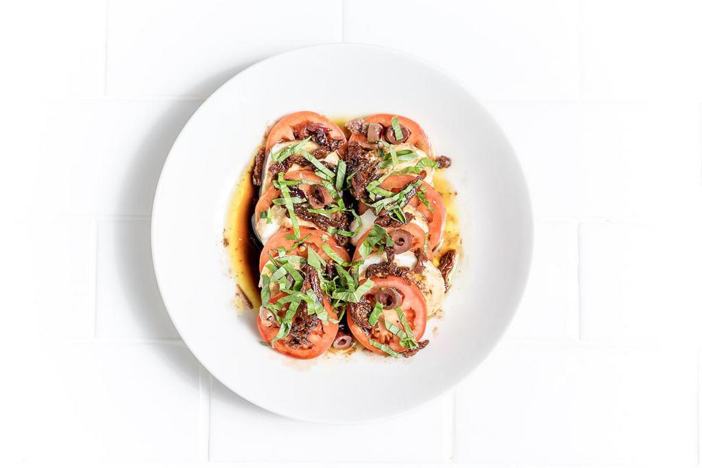 Caprese Salad · Fresh mozzarella, Roma and sun-dried tomatoes, fresh basil, Kalamata olives, olive oil and balsamic vinegar.