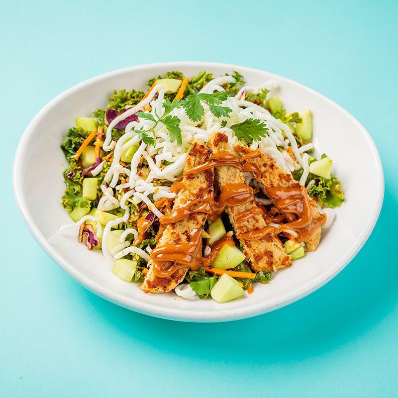 Kale Krunch Salad · Plant-based grilled chicken, Thai peanut sauce, raw kale, crispy rice noodles, red and green shredded cabbage, carrots, cucumber, cilantro lime dressing, and fresh cilantro. Vegan.