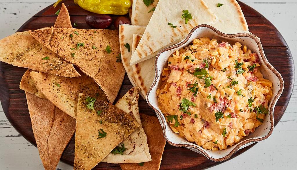 Spicy Pimento Cheese · Grated sharp cheddar, mayo, diced red peppers and a hint of Tabasco, served with soft or baked pita chips. Spicy and vegetarian.