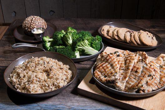 Chicken Family Meal · Eight fire-grilled chicken breasts, home-style mashed potatoes or 5-grain rice pilaf, fresh broccoli with garlic butter, and eight chocolate chip cookies.