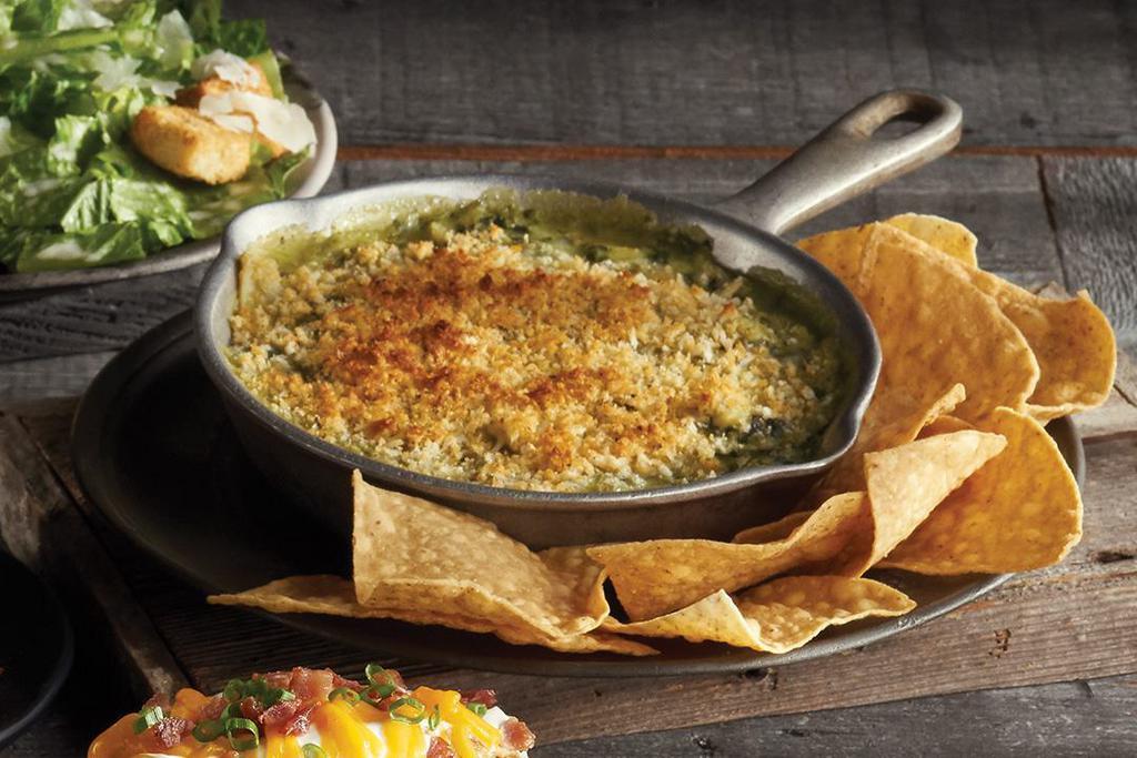 Baked Spinach & Artichoke Dip · Parmesan, Jack and cream cheeses beneath a breadcrumb topping. Served with tortilla chips.
