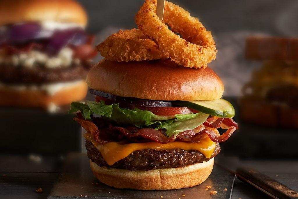Steakhouse Bacon Cheeseburger · Hand-formed, half-pound, Certified Angus Beef®, ground chuck, stacked high with Applewood-smoked bacon, sharp Cheddar cheese, lettuce, tomato, onion, house-made pickles, topped with onion rings.
