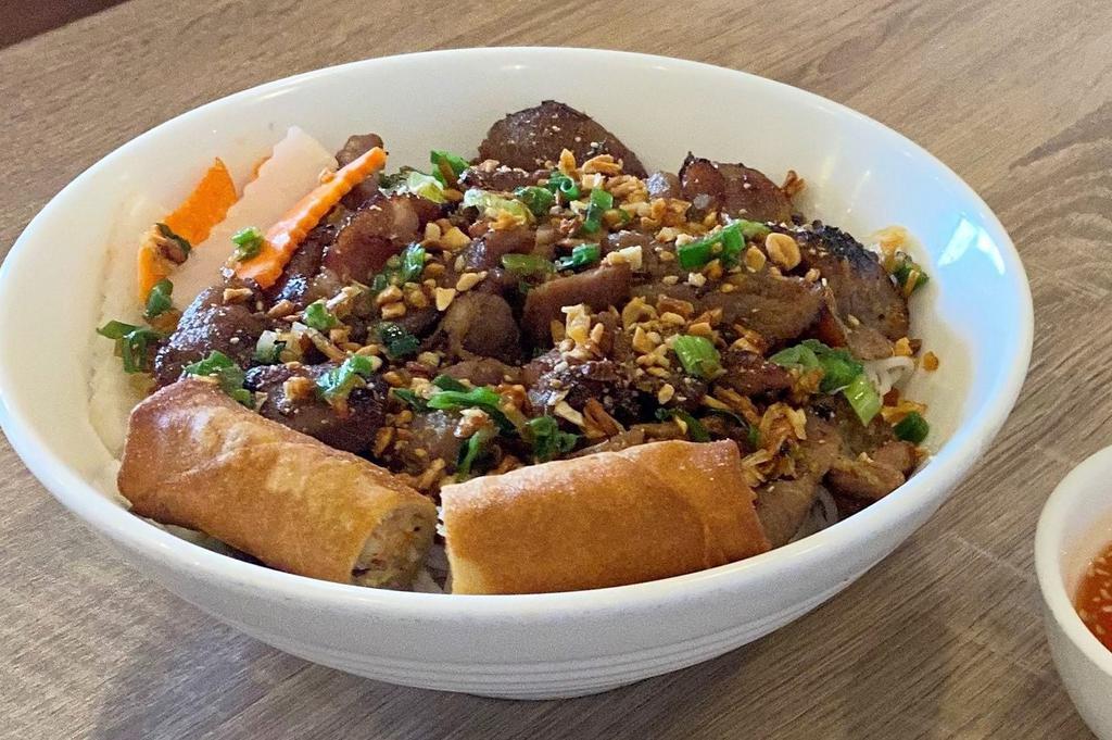 Bun Thit Nuong Cha Gio · Grilled sliced pork and egg roll over vermicelli and vegetables.