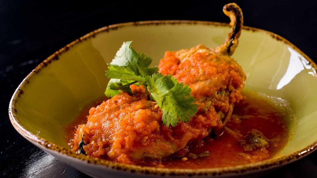 Chile Relleno con Queso · Roasted poblano pepper stuffed with queso fresco, served in a light tomato sauce with rice and beans.