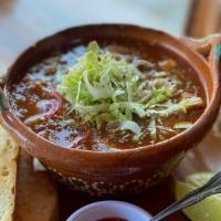 Pozole  · Pork hominy stew with guajillo broth served with two refried bean tostadas, queso, crema, on...