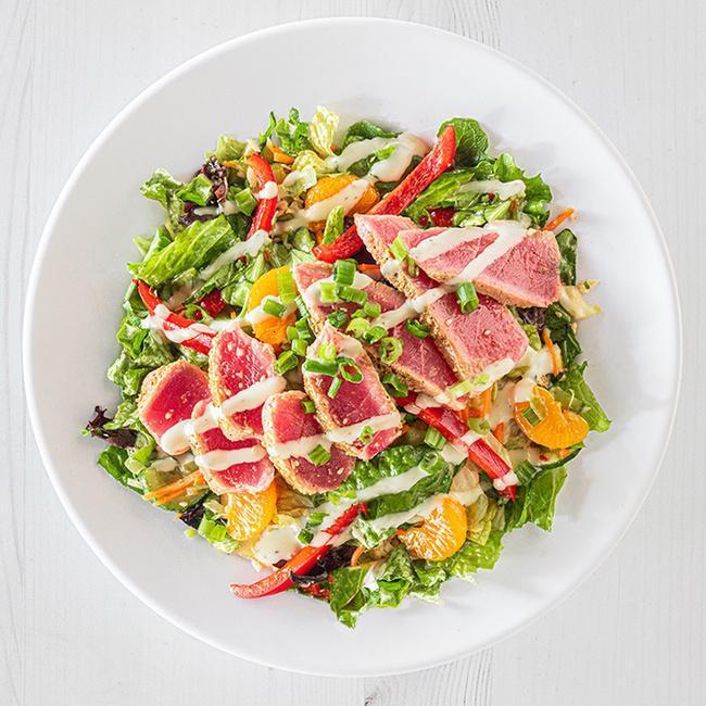 Seared Ahi Tuna Salad · Cooked medium rare, these seared ahi tuna medallions are served on a bed of mixed greens alongside Asian slaw in sweet mandarin ginger dressing, topped with mandarin oranges, red pepper, green onions and a drizzle of cucumber wasabi sauce. (700 cal.)