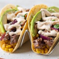Grilled Steak & Avocado Taco · This meaty taco features sliced marinated skirt steak on a bed of roasted poblano corn medle...