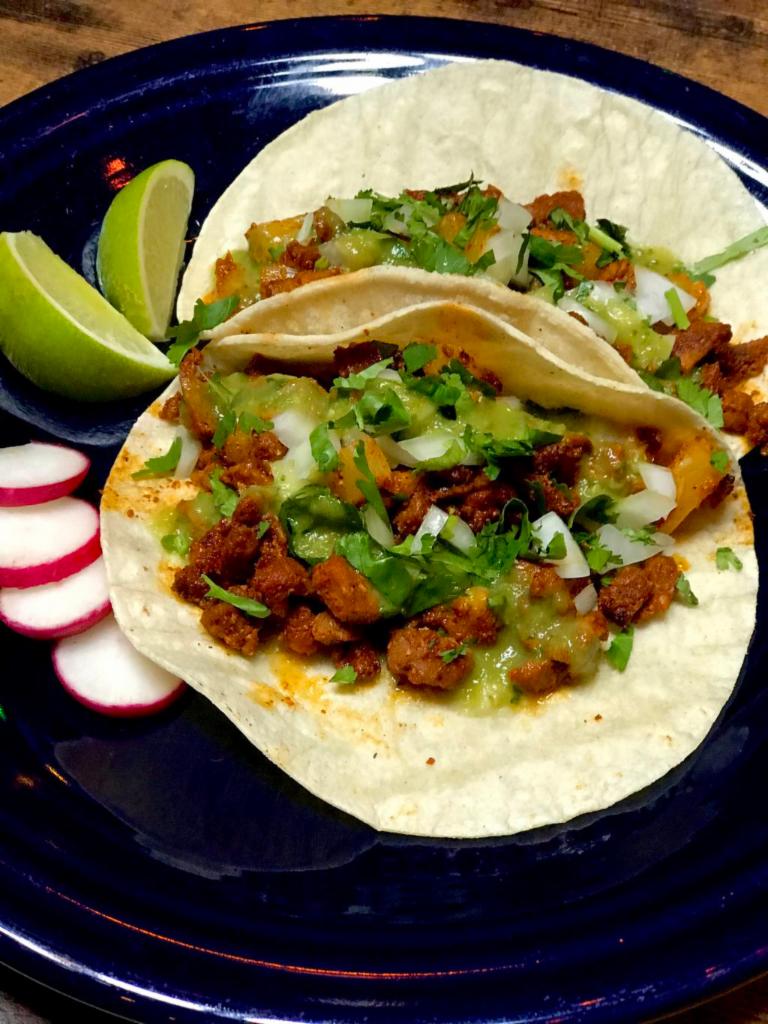 Al Pastor Tacos  · Spiced pork pineapple. Adobo marinated pork, pineapple and spices, topped with diced onions, cilantro and a side of avocado jalapeno salsa and lime. 2 tacos served on corn tortillas. Gluten free.