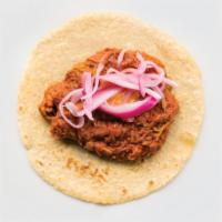Cochinita Pibil · Shredded pork cooked in a sweet, red achiote spice atop black beans. Served with Yucatan com...