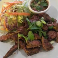 61. Crying Tiger · Charbroiled prime-cut beef marinated with Thai spices. Thinly sliced and served with Thai sp...