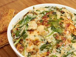Spinach Artichoke Dip · Made daily in house with fresh spinach, artichoke hearts, a variety of cheeses including our signature blend, garlic and seasonings. Served with an 8