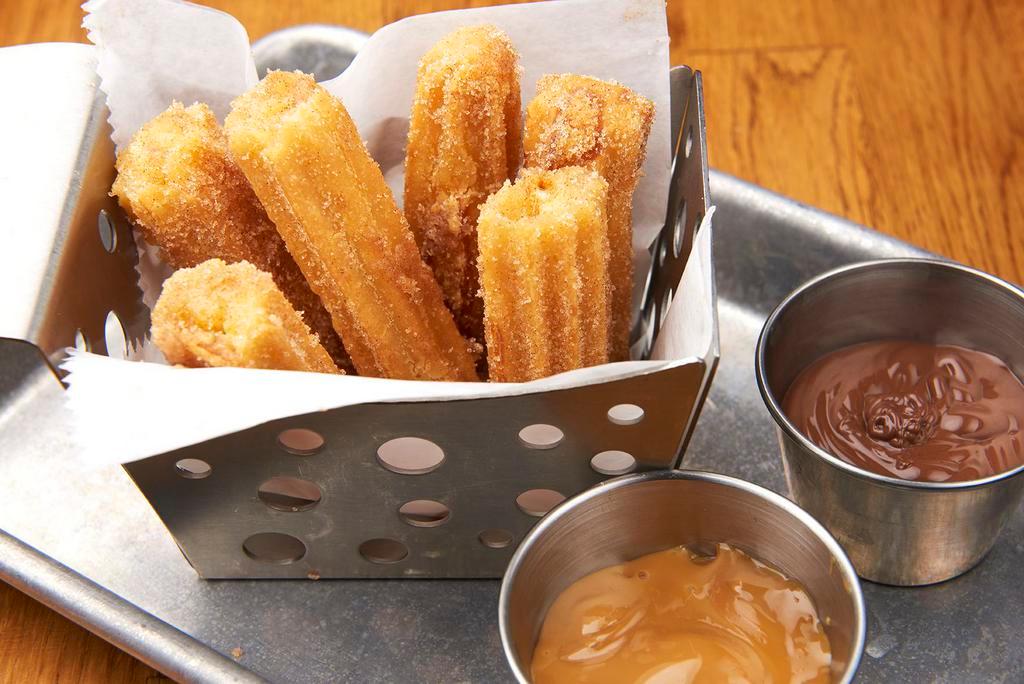 Churros · fried-dough pastry coated with cinnamon and sugar, served with homemade dulce de leche and hazelnut spread.