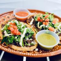 Serrano’s Huaraches · Fried masa dough with a refried pinto beans spread, topped with pico de gallo, crema and cot...