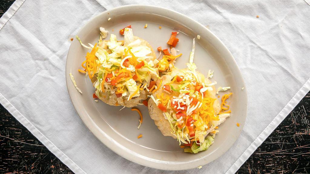 54. Puff Tacos · 2 puff flour tortillas filled wilh ground beef or shredded chicken sauteed and topped with shredded lettuce, tomatoes and shredded cheddar cheese.