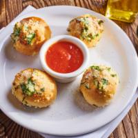 Garlic Knots · Pizza dough tied in a knot, baked and topped with parsley and garlic oil.  Served with a sid...