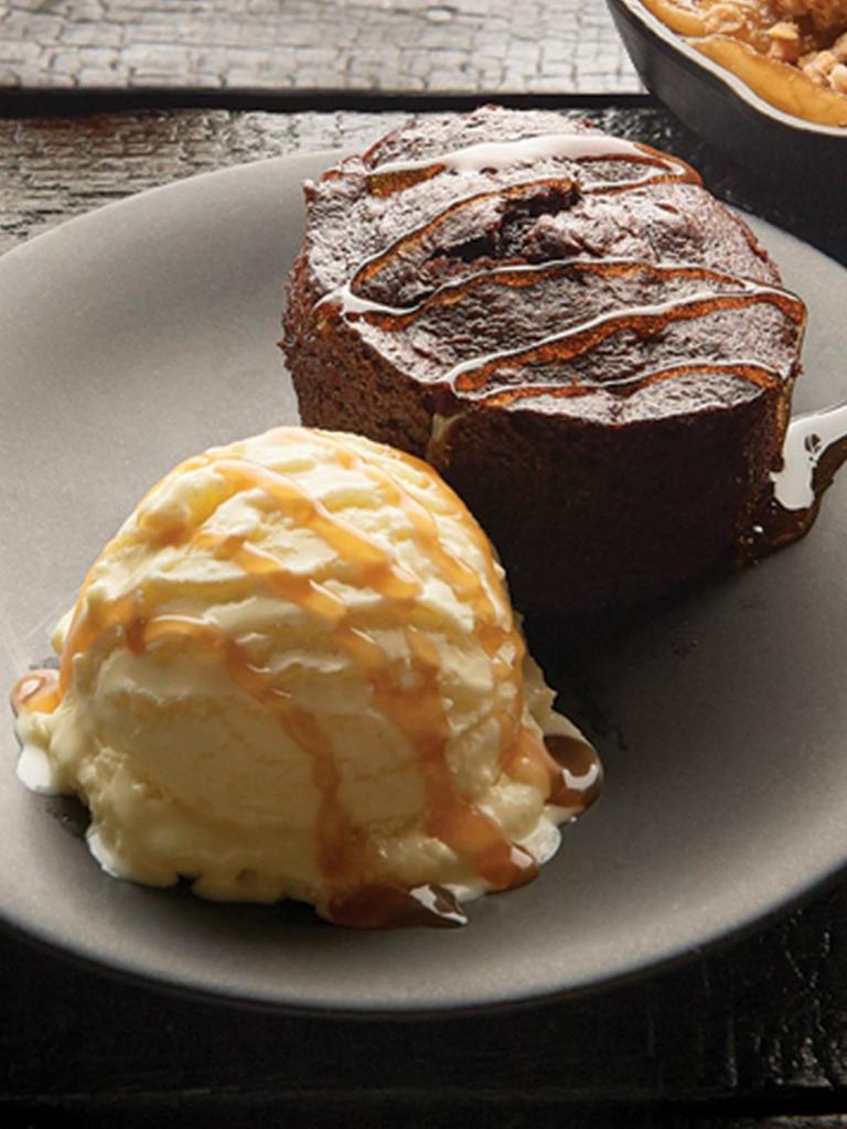 Chocolate Excess Cake · Rich chocolate mini-bundt cake filled with dark chocolate and topped with vanilla ice cream and chocolate sauce.