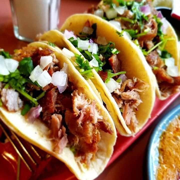 Carnitas Tacos Dinner · Slow cooked, simmered, roasted pork, creating a beautiful alternating texture of softness with caramelized crispness. Finished with diced white onions and cilantro and garnished with lettuce, mixed cabbage and lime wedge. Served with choice of rice and beans.