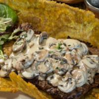 Patacon Momposino · Green plantain patacon topped with chicken breast or steak covered with mushrooms sauce.