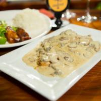 Pechuga Con Champinones · Grilled chicken breast covered with mushrooms sauce, white rice, salad, and sweet plantains.
