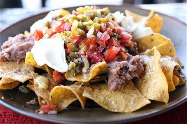 Nachos Supreme · Crispy corn tortilla chips covered in cheese sauce, topped with refried beans, ground beef or cheese, lettuce, pico de gallo, guacamole, and sour cream.
