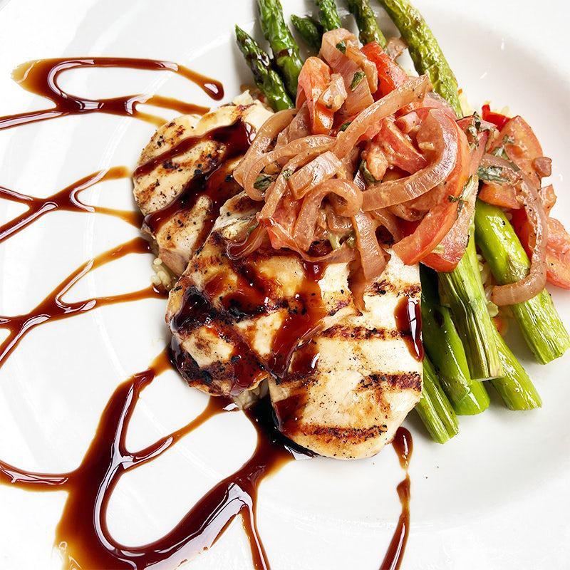 Mediterranean Chicken · Grilled chicken breasts served on rice pilaf and asparagus, with roma romatoes, balsamic caramelized onions and balsamic reduction. Light, but full of flavor!