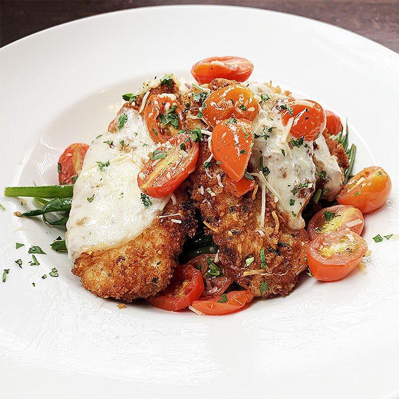 Chicken Tuscano · Lightly breaded, pan fried chicken breast topped with melted provolone cheese, and served over garlic mashed potatoes, sauteed green beans, and grape tomatoes in a white wine butter sauce.