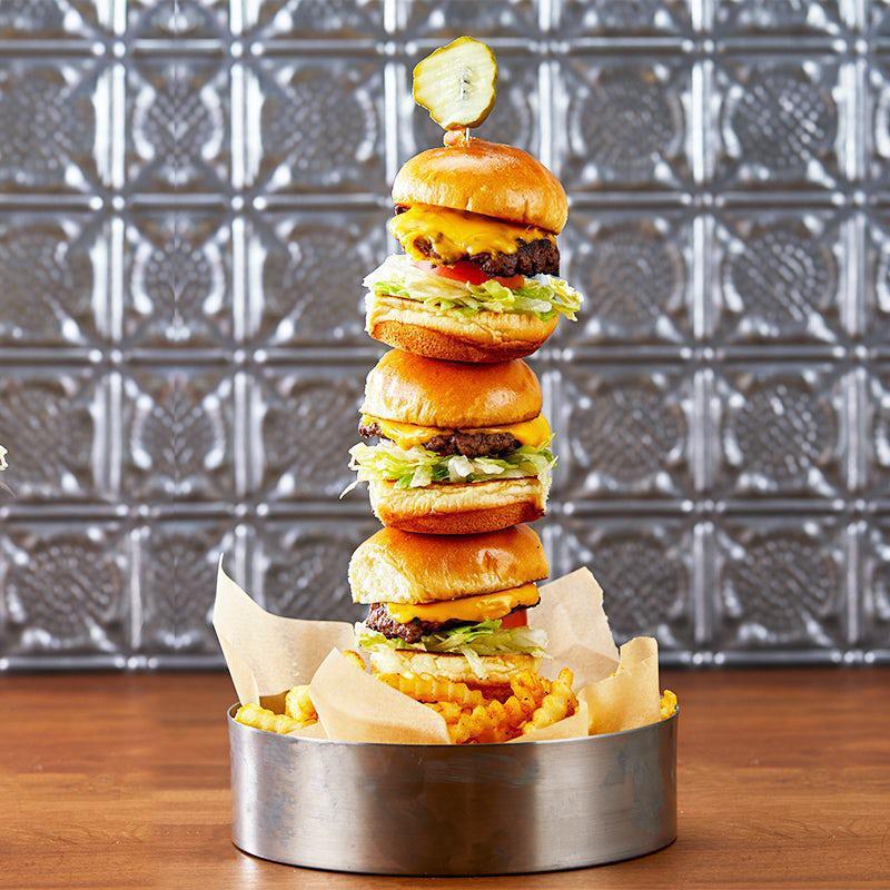 Cheeseburger Slider Tower · Juicy hamburger patties on brioche slider buns. Stacked high with crisp lettuce, onion, roma tomatoes, and American cheese. Served over french fries.