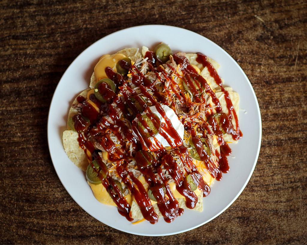 BBQ Nachos · Choice of pork BBQ, smoked chicken, or beef brisket. Topped with nacho cheese, jalapenos, sour cream, shredded cheese, and BBQ sauce.