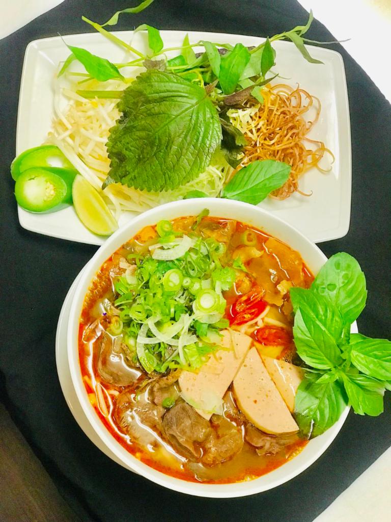 F4. Bun Bo Hue · Spicy beef noodle soup with round rice noodles, beef brisket and shank, tendon, pork sausage patties garnished with mixed onions and cilantro.