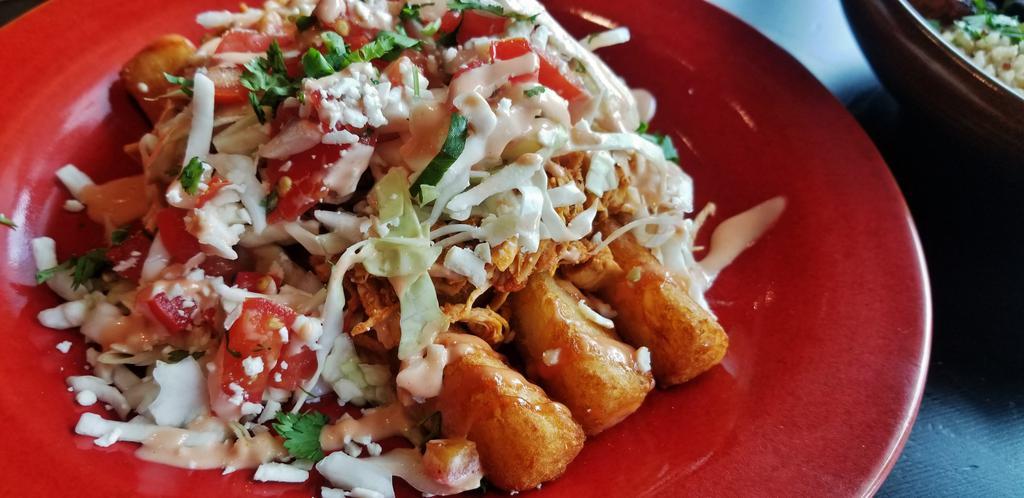 Salvadoran Fries · Yuca fries with shredded chicken sauteed with tomato and onion, topped with pico, cabbage, Cotija cheese and Rosado.