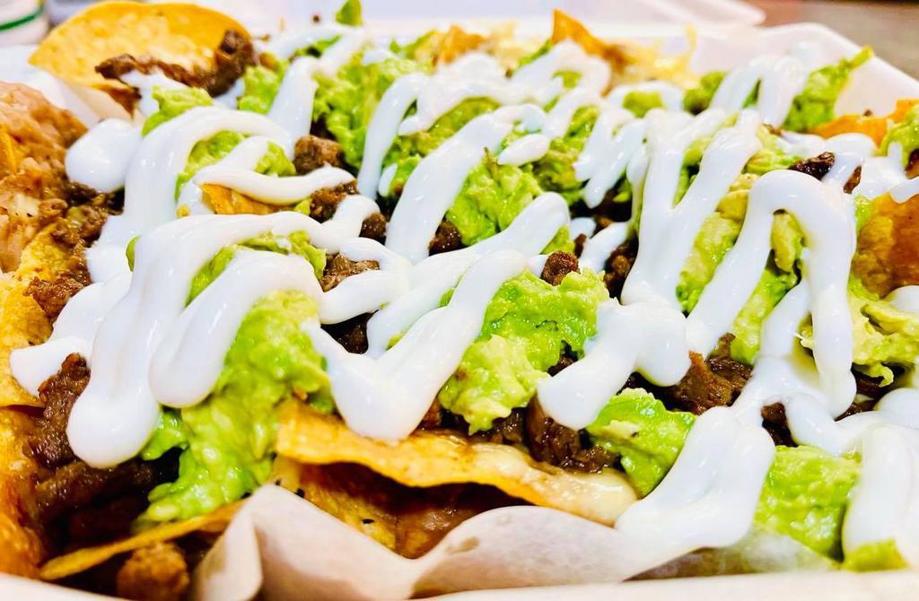 Nachos · Nachos with beans, cheese, meat, avocado and sour cream on top.