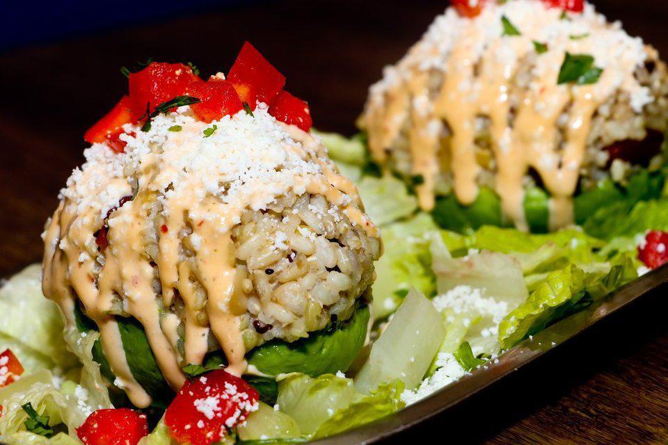 Stuffed Avocado · Ripe avocado, stuffed with quinoa and wild rice, topeed with red peppers, salsa roja, queso fresco, and cilantro.