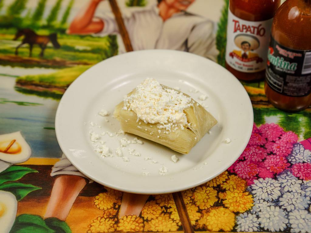Tamale de Elote · Sweet corn tamale topped with cheese and cream.