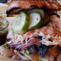 SMOKED PULLED BRISKET SANDWICH · Smoked pulled brisket sandwich, lettuce, coleslaw, homemade pickles, BBQ sauce on a pretzel ...