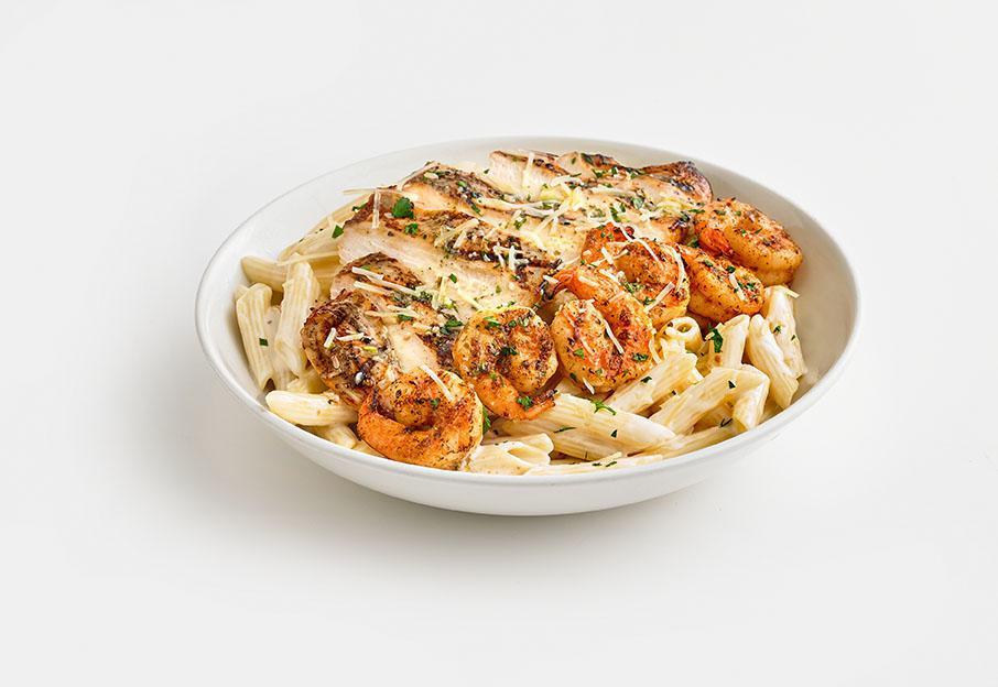 Chicken and Shrimp Pasta · Grilled chicken breast and Cajun shrimp over penne pasta tossed in a creamy Alfredo sauce and finished with lemon-garlic butter.