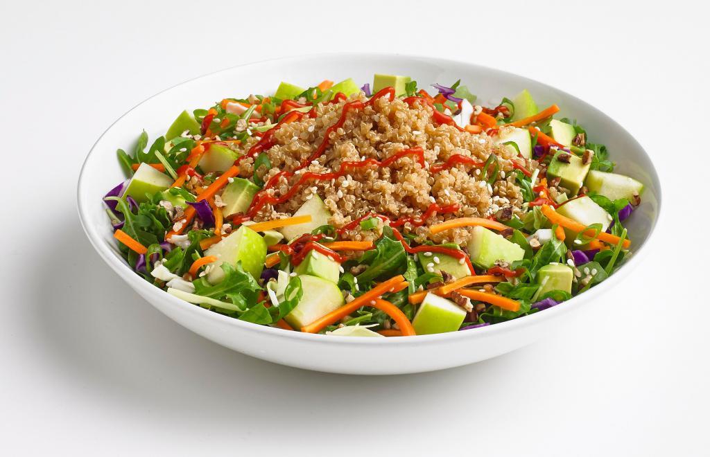 Quinoa Bowl · A quinoa rice blend on top of fresh spinach tossed in vinaigrette dressing with cabbage, shredded carrots, toasted pecans, sesame seeds, apples, and avocado. Garnished with green onion and Sriracha sauce.