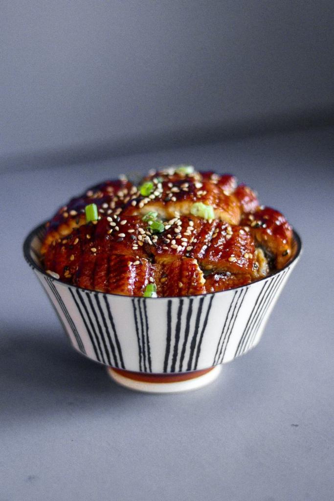 Donburi Eel Bowl · Torched Eel (5oz) served over furikake rice with tamago, ginger rose, wasabi, and a side of eel sauce, garnished with sesame seeds