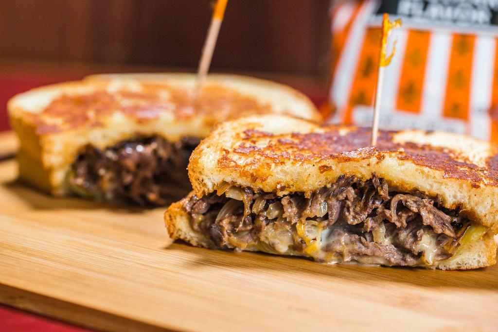 Southwestern Tri Tip · Marinated tri tip served on parmesan-crusted sourdough with a blend of cheddar and pepper jack cheeses, drizzled with southwest sauce, grilled onions, and an Ortega chile. 