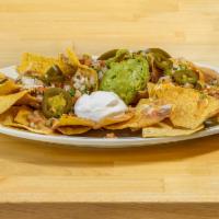 Loaded Nachos · A full plate of our homemade tortilla chips topped with meat, beans, cheese, sour cream, pic...
