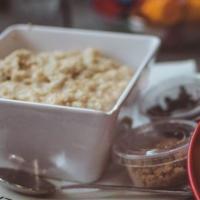 Old Fashion Oatmeal · A delicious bowl of hot oatmeal mixed with brown sugar and raisins with a side of milk.