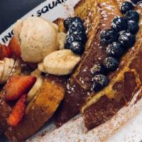 Tour de Fruit French Toast · Golden brown French toast topped with a delicious assortment of fresh strawberries, bananas ...