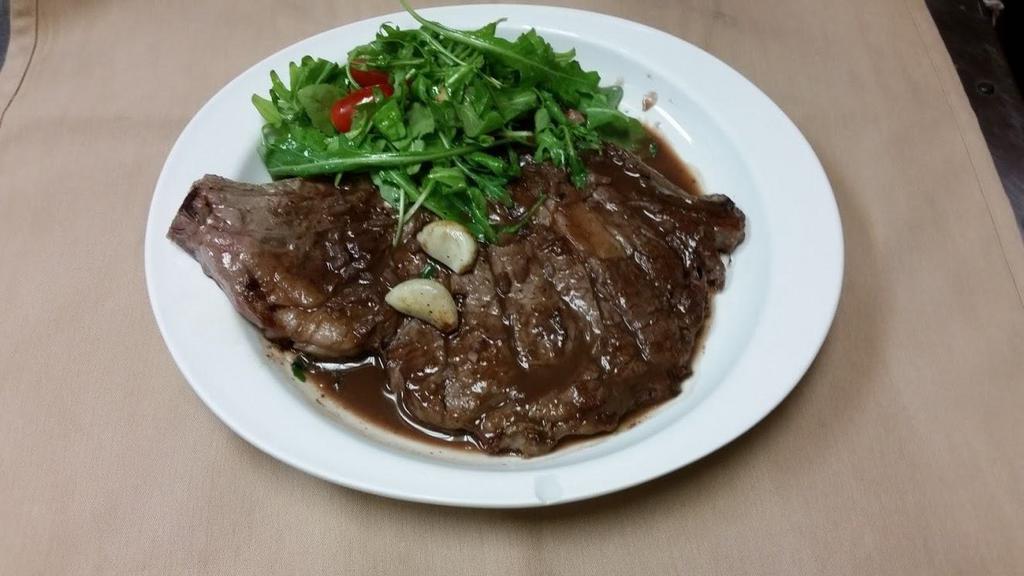 Tagliata di Manzo · Rib eye steak sliced and topped with arugula and cherry tomatoes in a light red wine sauce. Served with potatoes and vegetables.