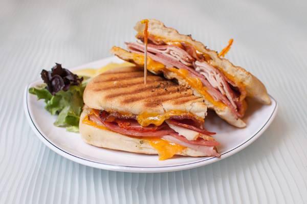 The Carnivore Panini · Black forest ham, smoked turkey, imported capicola, genoa salami, applewood smoked bacon, and plenty of aged NY cheddar. Served with house-made honey dijon.